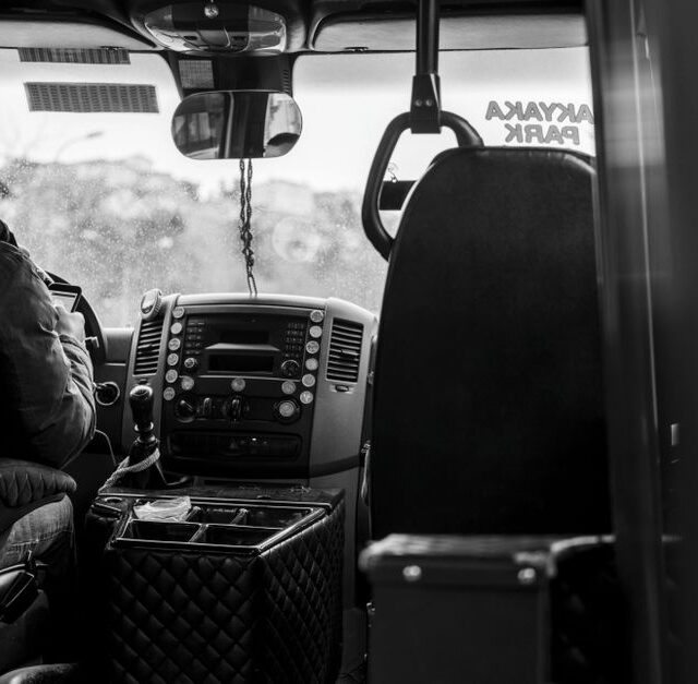Een buschauffeur rijdt door het Westland, met passagiers aan boord en een prachtig landschap op de achtergrond.