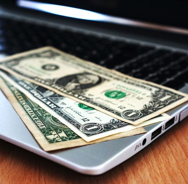 Een ondernemer die zijn financiën beheert met een laptop en notitieboekje, symboliseert het kiezen van de juiste zakelijke rekening.